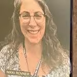 A framed photograph of a smiling person with glasses and long hair, showing nameplates.