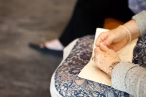 Person's hands holding a piece of paper, wearing a gray sweater and lace skirt.